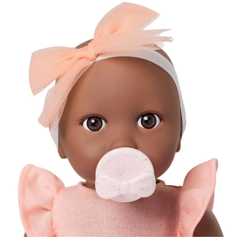 Babypuppe mit Schnuller – in einem orangefarbenen Kleid und mit einem Stirnband