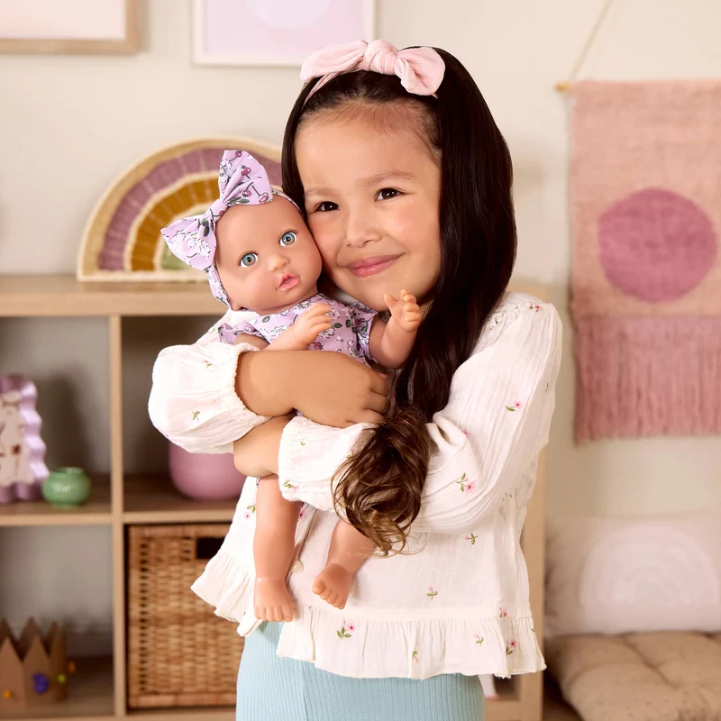 Babypuppe mit Schnuller – in einem Kleidchen mit Blümchenmuster und einem Haarband