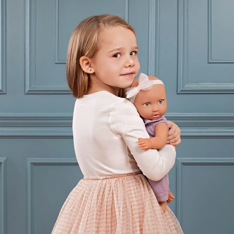 Babypuppe mit Schnuller im lila Musselinoutfit mit Stirnband
